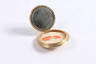 a gold locke with a fish in it on a white surface