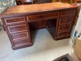 a wooden desk with drawers and a chair in the background