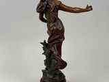 bronze statue of a woman holding a flower on a pedestal