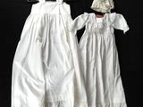 two white dresses and a hat are on a black background