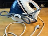un fer à repasser à vapeur bleu et blanc posé sur une table en bois