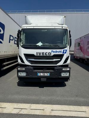 un camion blanc garé sur un parking à côté d'autres camions