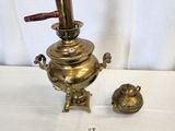 an antique brass tea kettle with a wooden handle and two small brass cups