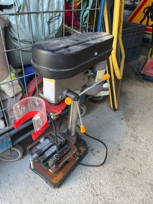 a drill on a table in a garage with other tools