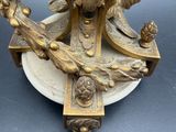 a gold clock on a stand with a bird on top of it