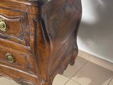 a small wooden chest of drawers on a tiled floor