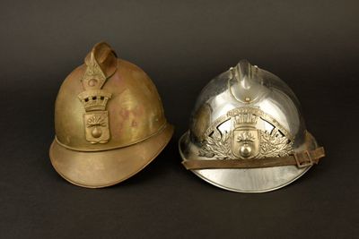 une paire de casques de pompiers posés sur une surface noire, avec un fond noir