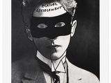 photographie en noir et blanc d'un homme en costume, portant un masque sur la tête