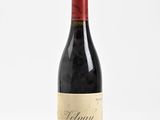 a bottle of red wine sitting on top of a white table