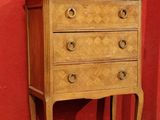 une petite commode exposée devant un mur rouge