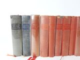 several old books are lined up in a row on a white surface