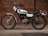 a white and green motorcycle parked in front of a brick wall