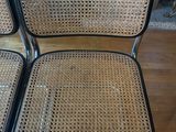 a set of four black and wicker chairs with chrome legs