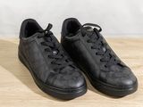 black leather sneakers with black laces on a wooden surface