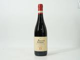 the bottle of red wine is sitting on a white surface