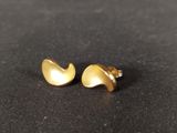 a pair of gold earrings sitting on top of a black surface