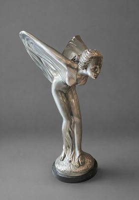 une statue en argent représentant une femme ailée, posée sur un socle noir