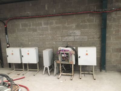 quatre boîtiers électriques posés dans une pièce avec un tuyau