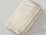 a silver cigarette case with a label on it sitting on a table