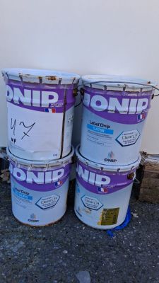 trois seaux de peinture posés par terre près d'un mur