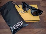 Des lunettes de soleil Fendi et leur étui posés sur un parquet, à côté d'une autre paire de lunettes de soleil