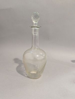 une petite bouteille en verre posée sur une table, à côté d'une bouteille en verre encore plus petite