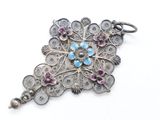 a close up of a silver broochet with pink and blue stones