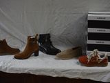 several pairs of shoes are lined up on a shelf next to a stack of boxes