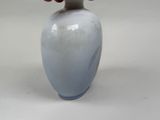 a vase with a red flower in it on a white table