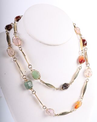 collier composé de pierres multicolores et de chaînes dorées, porté par un mannequin blanc