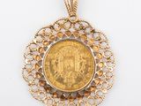 a close up of a gold coin in a pendant on a white surface