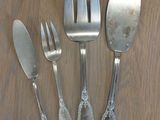 four forks, a knife, and a spoon on a table