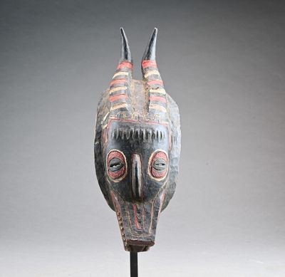 une image représentant un masque en bois posé sur un socle, sur fond gris