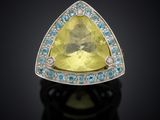 a close up of a yellow sapphire and diamond ring on a black surface