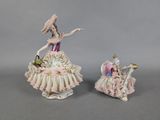 pair of porcelain figurines of a woman in a pink dress and a lady in a white dress