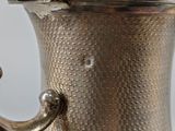 a silver tea pot with a handle on a table