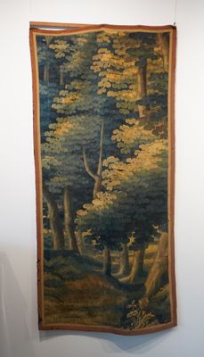 une tapisserie accrochée au mur d'une pièce, représentant un cerf dans les bois