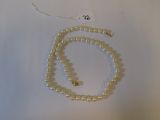 a white beaded necklace with a gold clasp