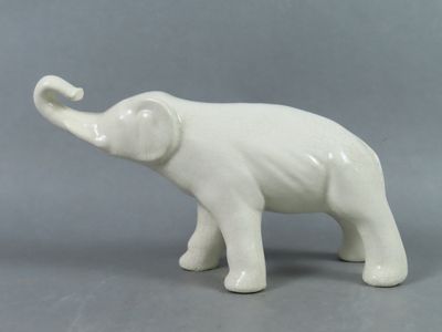 une figurine d'éléphant blanc posée sur une surface grise