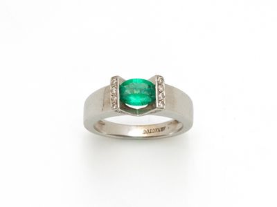 gros plan d'une bague avec une pierre verte et des diamants