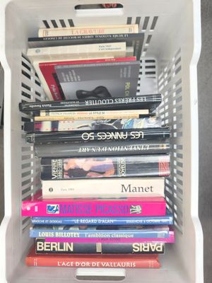 many books in a white basket on a table