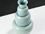 a stack of three blue vases sitting on a white table