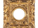un cadre doré richement décoré, avec un miroir circulaire au centre