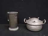 a silver pot and a silver cup sitting next to each other