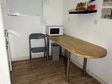 une table avec un micro-ondes et une chaise dans la pièce