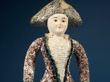 a ceramic figurine of a woman with a hat and dress