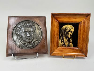 deux plaques en bronze représentant un homme et une femme, dans un cadre en bois