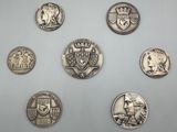 six types différents de pièces d'argent sur une surface blanche
