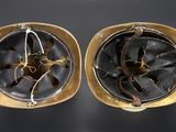 pair of antique brass helmets on a black background