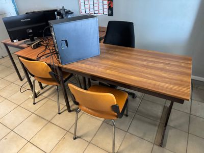 des tables et des chaises dans une pièce, avec un ordinateur portable posé dessus